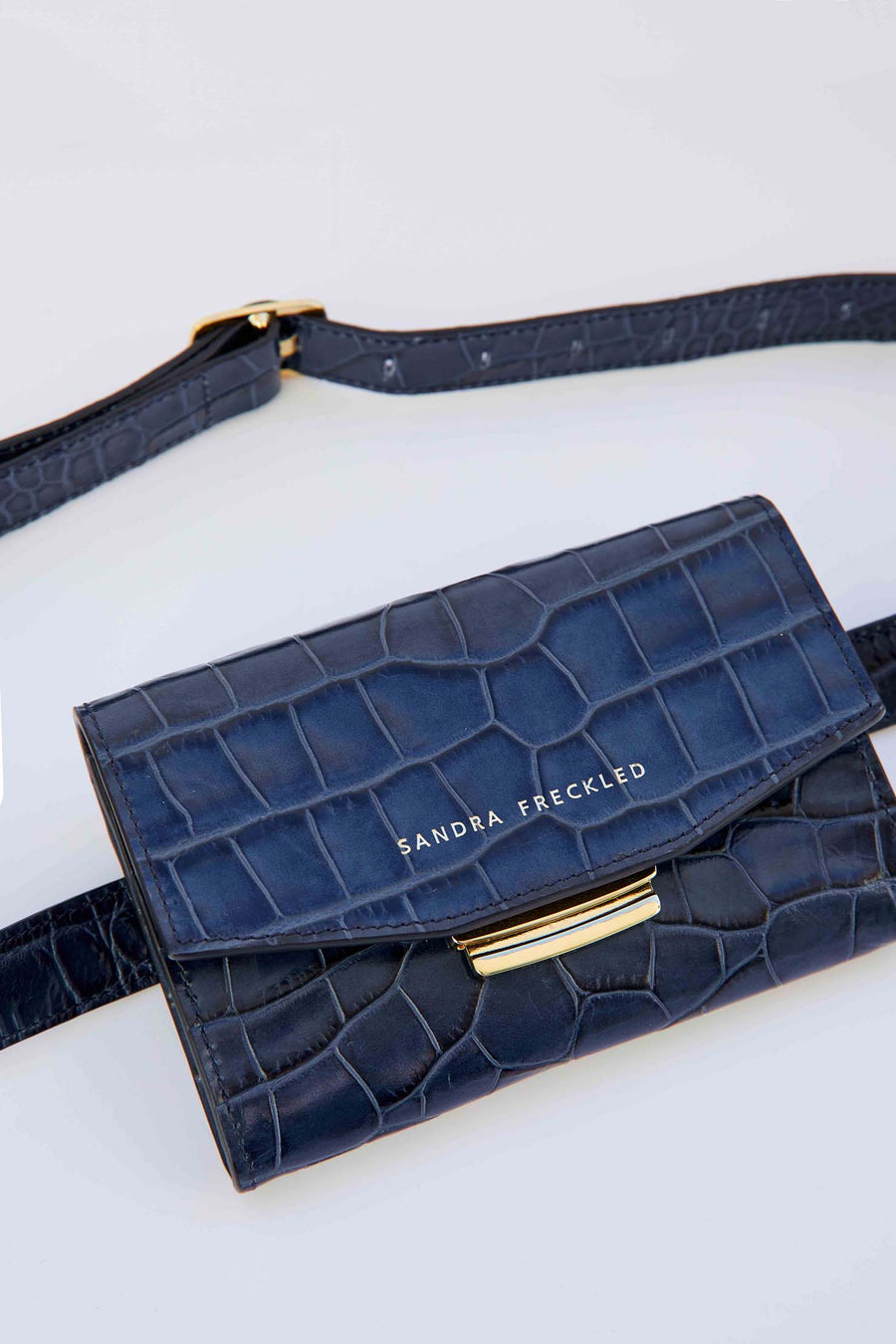 MACARENA Bolso de piel de cocodrilo en color azul marino con correa y cierre dorado. Es un bolso estilo riñonera y bandolera que puede utilizarse como bolso de mano - SANDRA FRECKLED bolsos de mujer